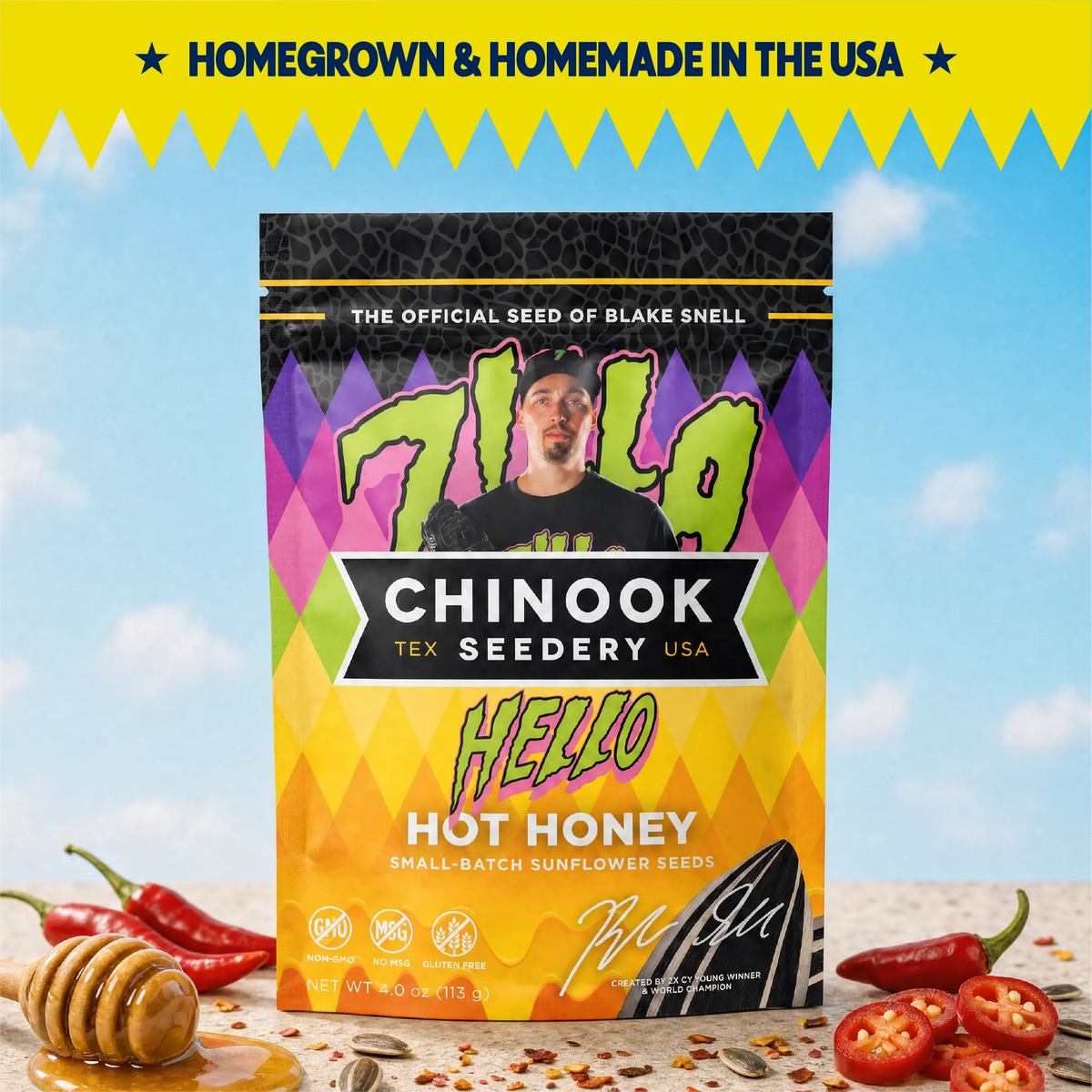 Chinook Seedery Hello Hot Honey sunflower seeds 4 oz bag with a honey dipper and red chili peppers under a blue sky