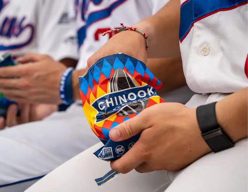 Person holding a colorful bag of Chinook flour with a baseball player in the background.